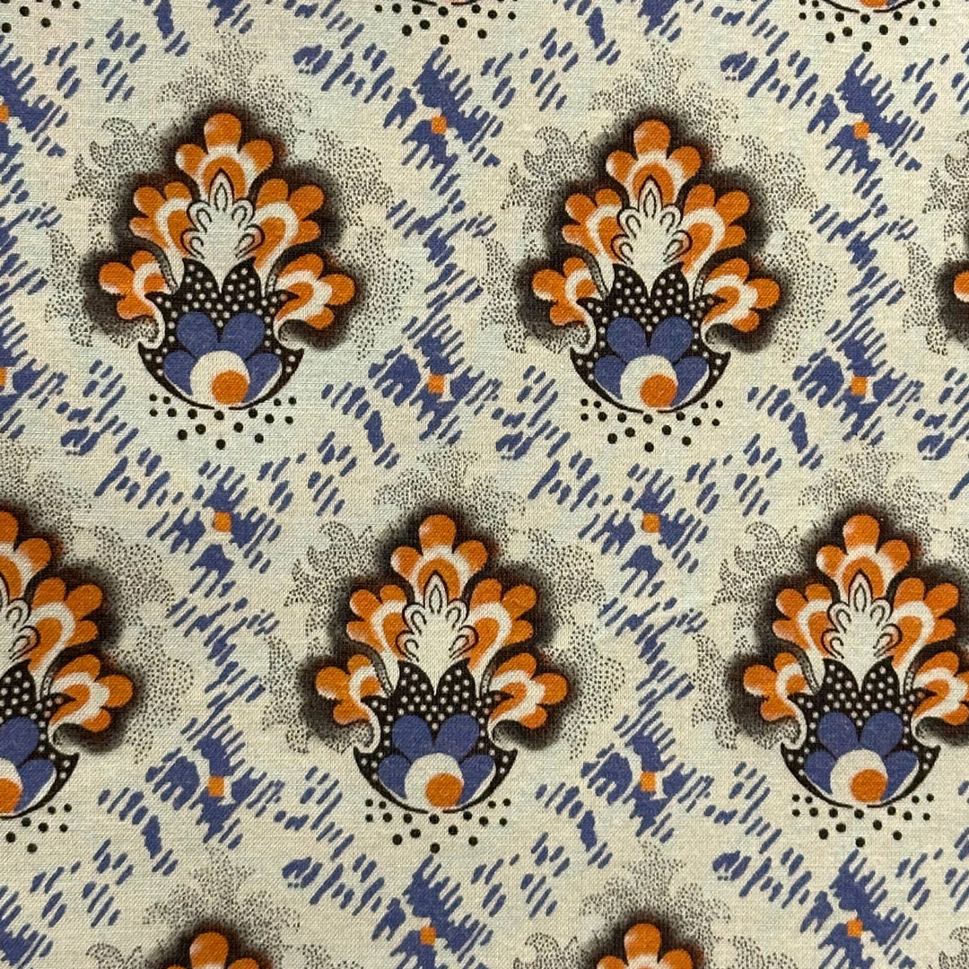 Patterned fabric with decorative peacock design in orange, blue, and black on a beige background.