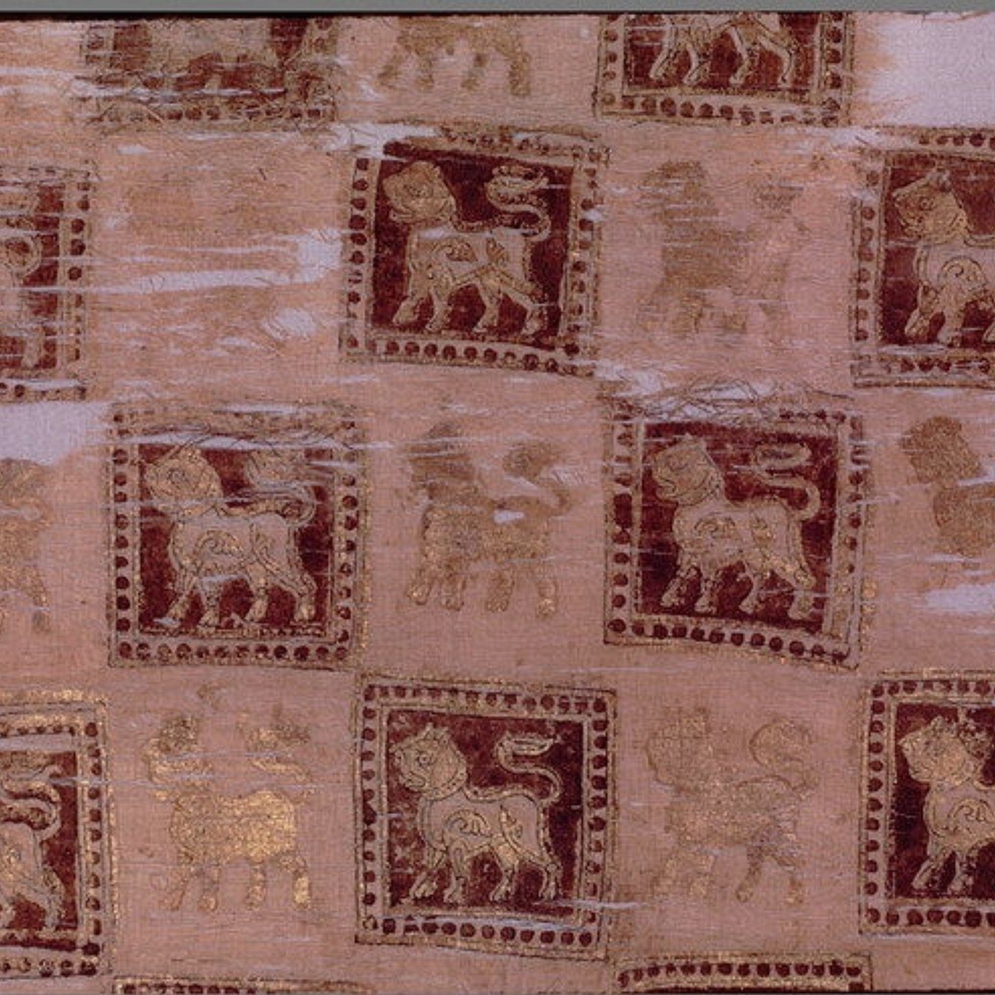 An ancient textile or papyrus fragment featuring repeated square motifs of stylized lions in dark red and gold, set against a light beige background with a white border.