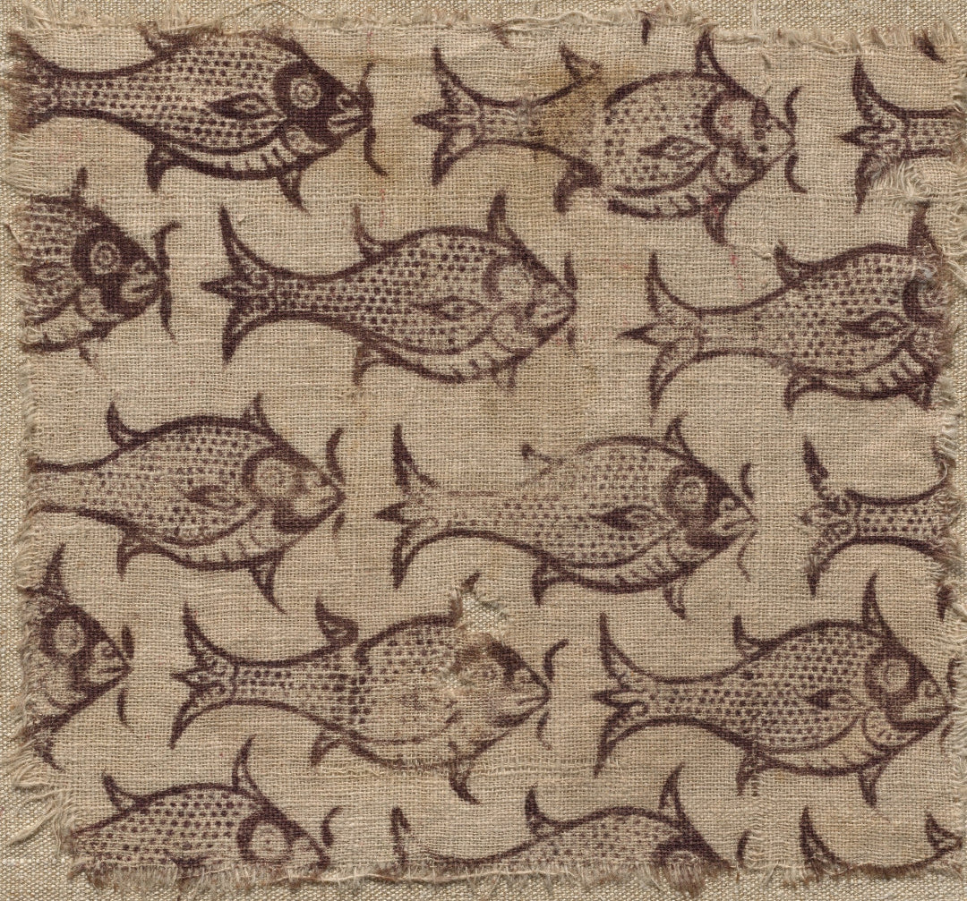 A square fabric swatch featuring a repeating pattern of stylized fish in dark brown on a textured beige linen-like background with frayed edges.