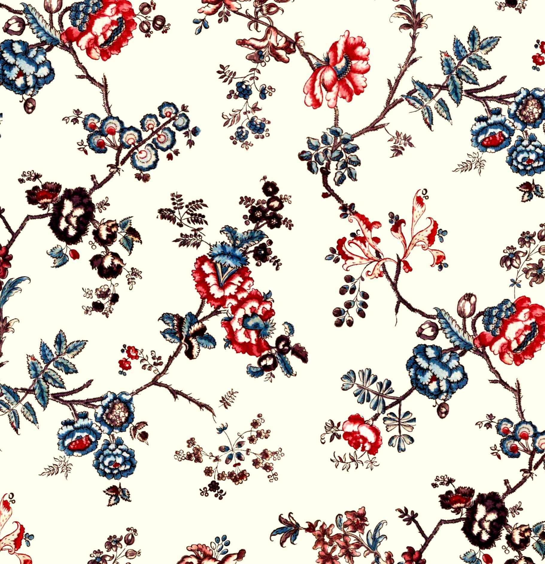 A repeating floral pattern on a warm cream background, featuring embroidered-style blossoms and leaves in red, blue, brown, and black.