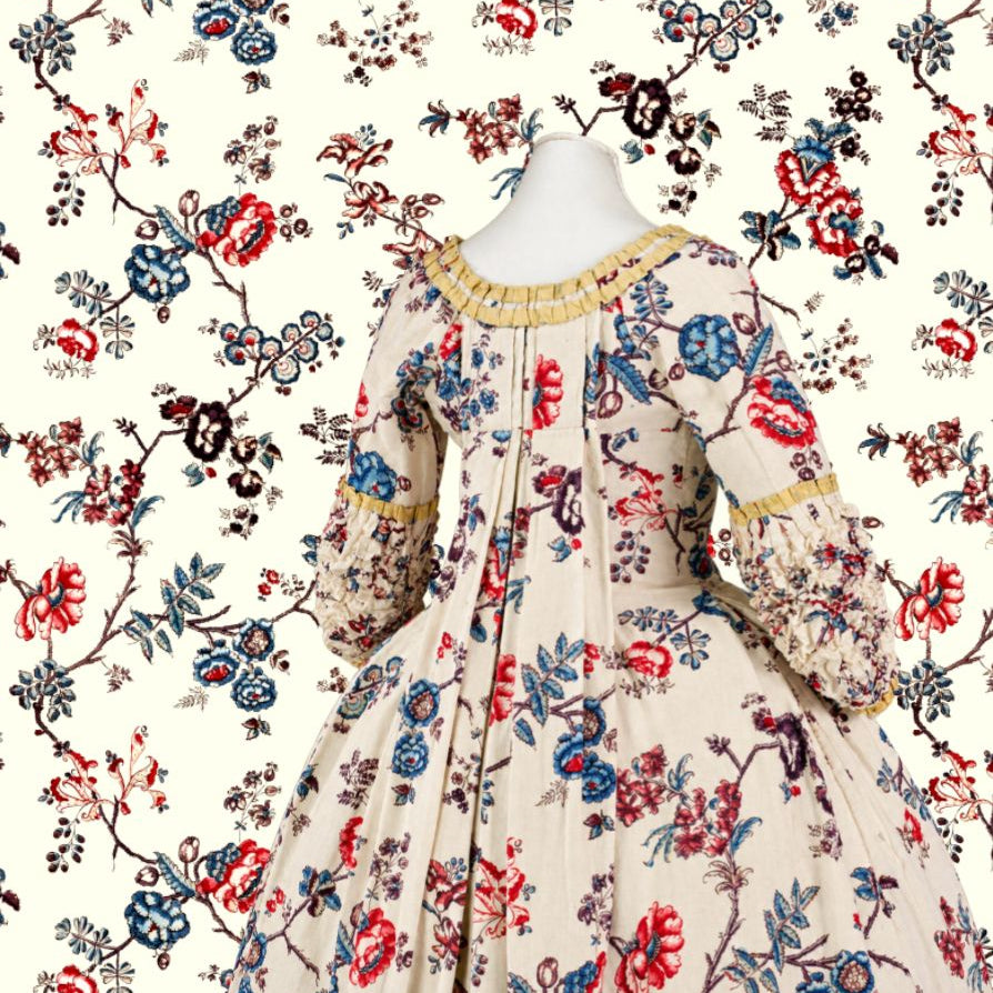A vintage-style long-sleeve dress displayed on a mannequin torso against a matching floral patterned backdrop. The dress has a cream base with an allover floral print in red, blue, and dark brown, with gold trim around the neckline and cuffs.