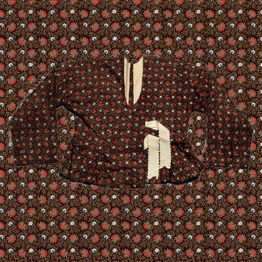 Close-up of a patterned fabric with small red and white shapes on a brown background