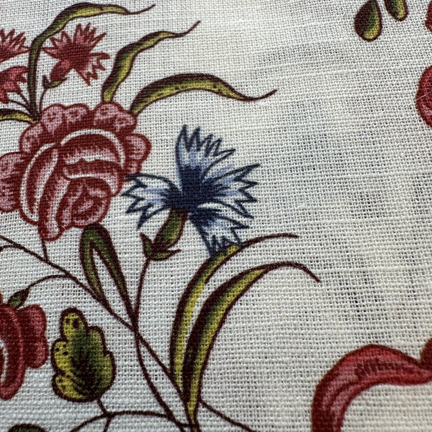 Close-up of floral embroidery on fabric with red, blue, and green flowers.