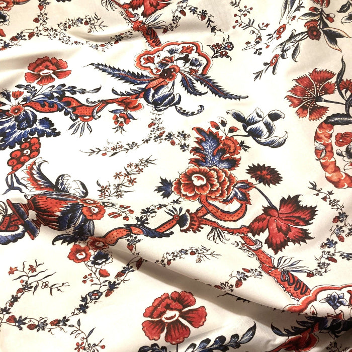 Floral and bird patterned fabric with red, blue, and black colors on a white background.