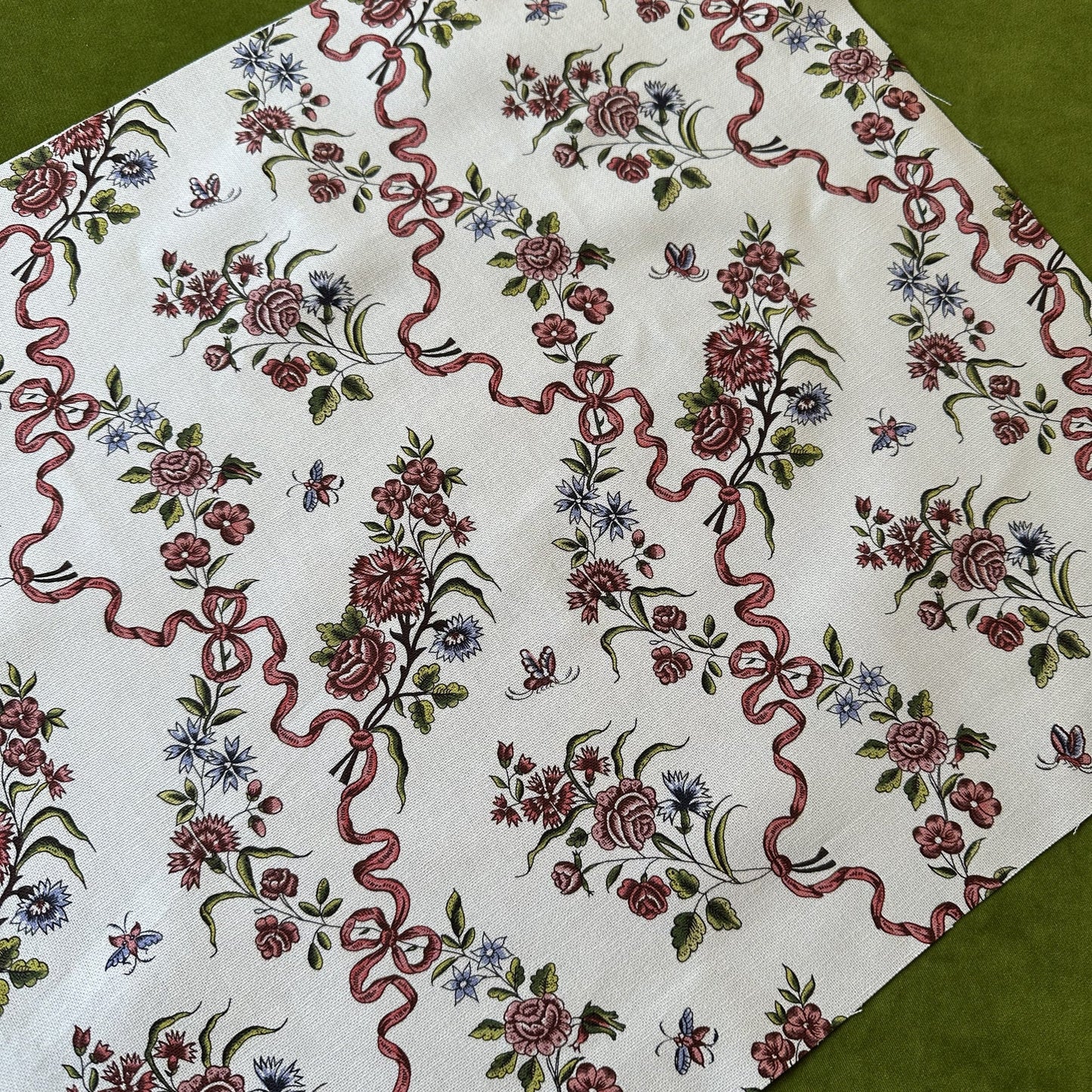 Floral and ribbon patterned fabric on a green background